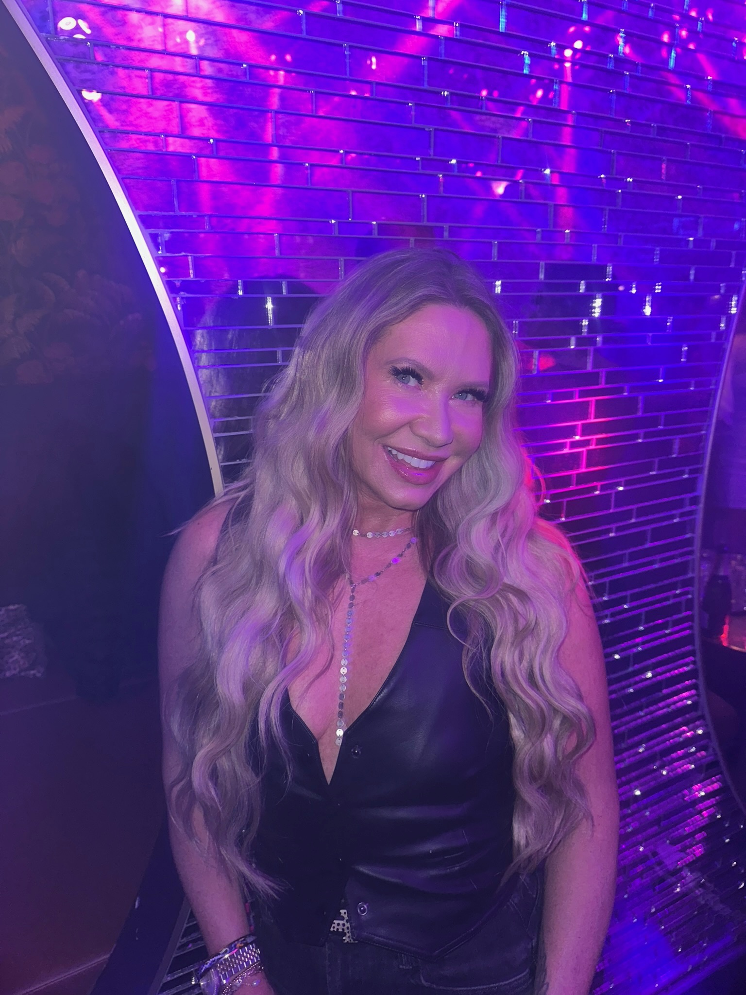 Jennifer Bass Billman with long, blended extensions under purple lighting, NBR and luxury extensions specialist in Oklahoma City.